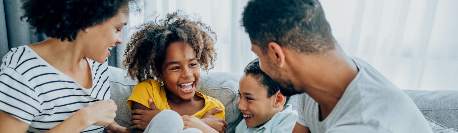 Family of four laughing on a couch