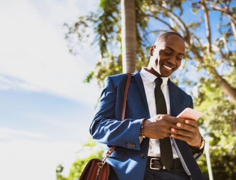 Young businessman using mobile phone while walking